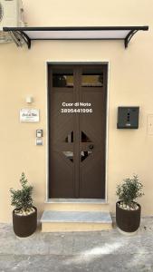 Una puerta de entrada de un edificio con dos plantas en macetas. en Cuor di Noto, en Noto