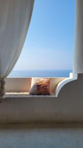 ein Fensterbrett mit einem Kissen und einem Fenster mit Meerblick in der Unterkunft Salina Castel Vinci in Rinella