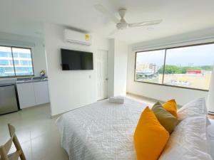 1 dormitorio con 1 cama con almohadas amarillas y TV en Magico Apartaestudio con Piscina 1 Habitacion PR66C en Montería