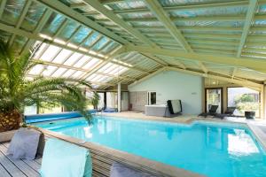 an indoor swimming pool with a glass ceiling at Gîte Piscine et Jacuzzi intérieurs in Cherveix-Cubas