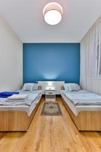 two beds in a room with a blue wall at Apartamenty KOMBI in Nowy Targ