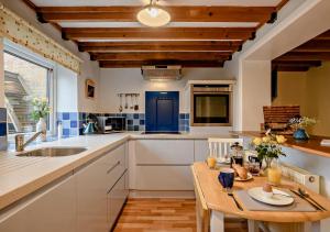 a kitchen with white cabinets and a wooden table at Cobbley Cottage in Little Snoring