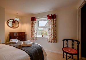 a bedroom with a bed and a window and a chair at Cobbley Cottage in Little Snoring