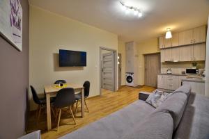 sala de estar con sofá, mesa y cocina en Apartamenty KOMBI, en Nowy Targ