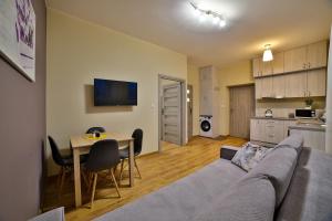 a living room with a couch and a table and a kitchen at Apartamenty KOMBI in Nowy Targ