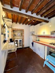 una gran cocina con armarios blancos y un taburete azul en Charming House Isola di Capraia Casa Carlo Alberto, en Capraia