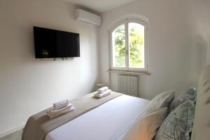 - une chambre avec un lit et une télévision murale dans l'établissement Casa Ema, à Peschiera del Garda