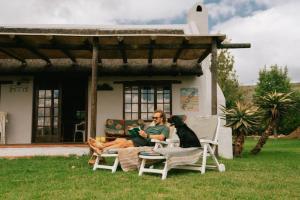 a man sitting on a chair with a dog on a patio at Rivertime in Malgas