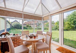 a conservatory with a table and chairs and windows at Badgers Hideaway in Helhoughton
