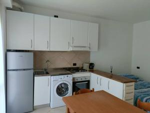 a kitchen with white cabinets and a washer and a table at Appartamento Aeroporto e Fiera in Seriate