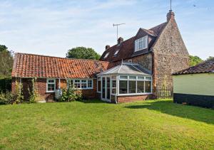 an exterior view of a brick house with a conservatory at Badgers Hideaway in Helhoughton