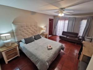 a bedroom with a large bed and a couch at Villa Stella Guest House in Edenvale