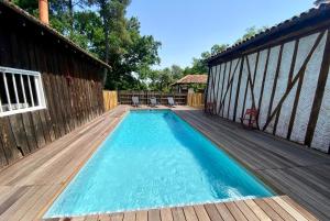 una piscina en una terraza de madera con una casa en Authentique villa du XIX e siècle avec piscine, en Lue