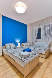 two beds in a bedroom with a blue wall at Apartamenty KOMBI in Nowy Targ