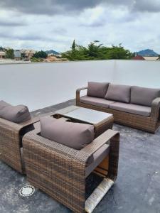 two wicker chairs and a couch on a roof at Aapartments in Abuja