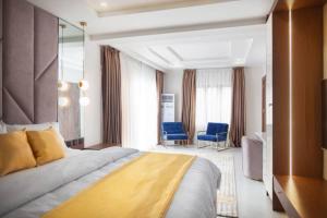 a hotel room with a bed and two blue chairs at Aapartments in Abuja