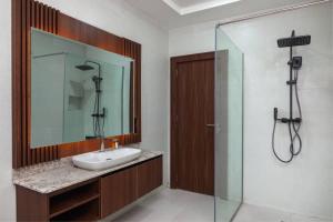 a bathroom with a sink and a shower with a mirror at Aapartments in Abuja