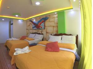 2 camas en una habitación con un pájaro en la pared en Hostal El Rey, en Baños