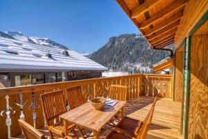 a wooden deck with a wooden table and chairs at La Savoyarde in Châtel