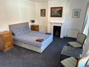 a bedroom with a bed and a chair and a fireplace at Luton Town House Near AIRPORT in Luton