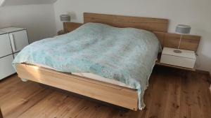 um quarto com uma cama de madeira e um edredão azul em Thomas's Loft em Stühlingen