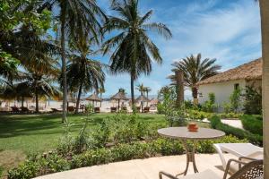 d'une terrasse avec une table, des chaises et des palmiers. dans l'établissement Hotel Royam, à Saly Portudal