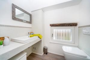 uma casa de banho branca com um lavatório e um espelho em Jacaranda em Udine