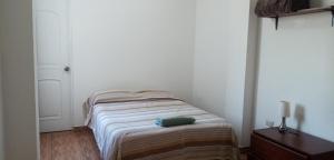 una piccola camera bianca con un letto in una stanza di Alojamiento del Norte a Chiclayo