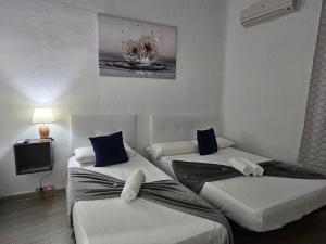 dwa łóżka w małym pokoju z telewizorem w obiekcie Casa Lemus w Madrycie
