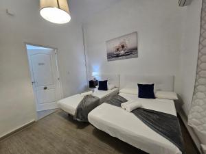 2 camas en una habitación pequeña con puerta en Casa Lemus, en Madrid