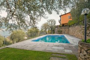 a swimming pool in a yard next to a house at ApartmentsGarda - Residence Pasola in Brenzone sul Garda