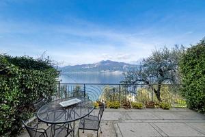 a table and chairs on a patio with a view of a lake at ApartmentsGarda - Residence Pasola in Brenzone sul Garda