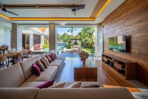 a living room with a large couch and a tv at The Amarta Villa in Jimbaran