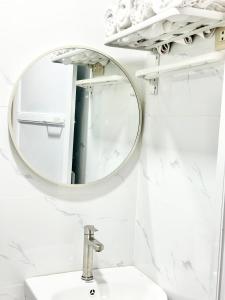 a bathroom with a round mirror above a sink at Olongapo Lawud - 3mins Walking Distance to Inflatable Island and Beaches in Olongapo