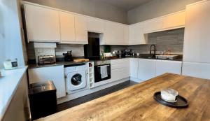 een keuken met witte kasten en een houten tafel bij Central - Business Stays - Relocating in Harrogate