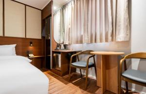 a hotel room with a bed and a table and chairs at H Avenue Hotel Chungjangro in Gwangju
