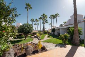 a garden with palm trees and a building at Makāi Bungalows in Playa del Aguila