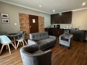 a living room with a couch and chairs and a kitchen at Cozy In Jozi in Edenvale