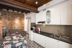 a kitchen with white cabinets and a brick wall at Arcadia in Verona