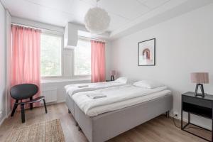 a white bedroom with a bed and a chair at 2ndhomes Tampere "Tammerinpuisto" Apartment in Tampere