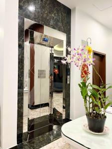 La salle de bains est pourvue d'un miroir et d'un vase avec des fleurs sur une table. dans l'établissement SAFFRON Dalat, à Đà Lạt