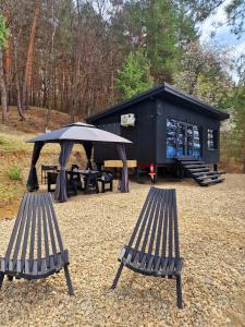 a black cabin with two benches and an umbrella at Nomad Lake Cabins in Rugineşti
