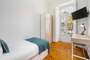 a bedroom with a bed and a desk and a window at Modern Nomad Hub Stylish Spaces for Remote Living in Lisbon