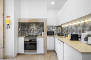 a kitchen with white cabinets and a stove top oven at Modern Nomad Hub Stylish Spaces for Remote Living in Lisbon