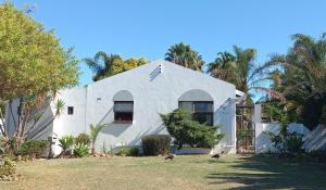 una casa blanca con dos gatos parados frente a ella en 19 on Robyn en Durbanville