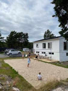 um grupo de pessoas brincando com um papagaio na areia em Summerhouse in south of Norway with privat boat house. em Arendal