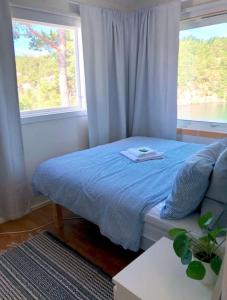 Un dormitorio con una cama azul y una ventana en Summerhouse in south of Norway with privat boat house. en Arendal