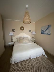 een slaapkamer met een groot wit bed en 2 lampen bij Le Chalet de Malo in Biscarrosse