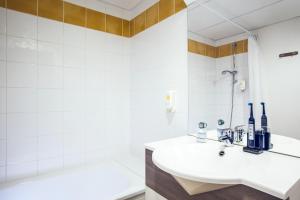 a white bathroom with a sink and a tub at Appart'hotel Vacancéole Paris Quai de Marne in Nogent-sur-Marne +6 photos