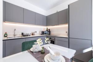 a kitchen with white cabinets and a table with flowers at Elegant apartment/2 in Buckinghamshire